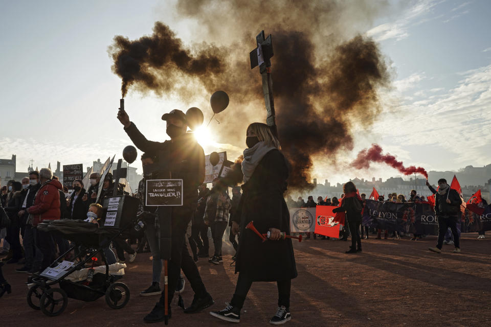 The owners of shops, bars and restaurants hold flares during a demonstration against the closure of their establishments in Lyon, central France, Monday, Nov. 23, 2020. France has surpassed 2 million confirmed cases of coronavirus, the fourth-highest total in the world. (AP Photo/Laurent Cipriani)