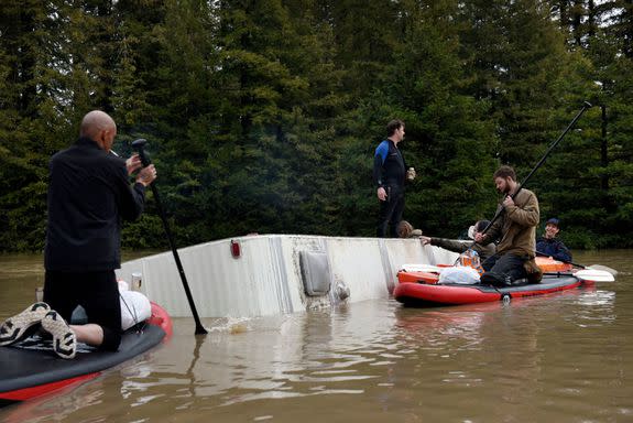 People gathered on a partially submerged RV in the flood waters of the Russian River.