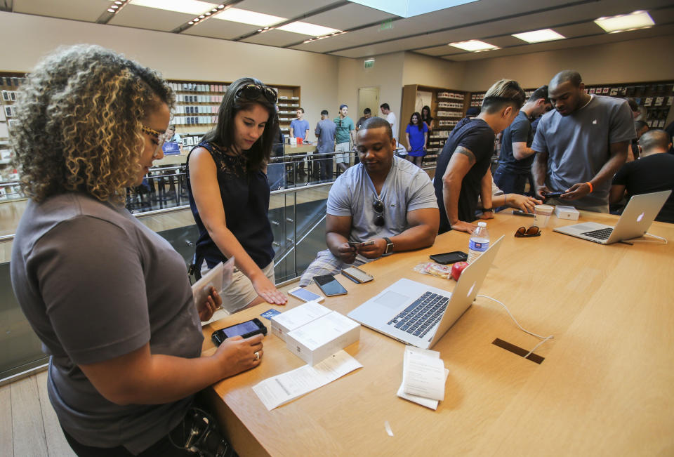 An Apple employee processes a transaction as customers purchase Apple's iPhone 6s and iPhone 6s Plus smartphones Friday, Sept. 25, 2015 at the Apple store at The Grove in Los Angeles. Apple is counting on sales of the new iPhones to maintain its position as one of the most profitable, and valuable, companies in the world. (AP Photo/Ringo H.W. Chiu)