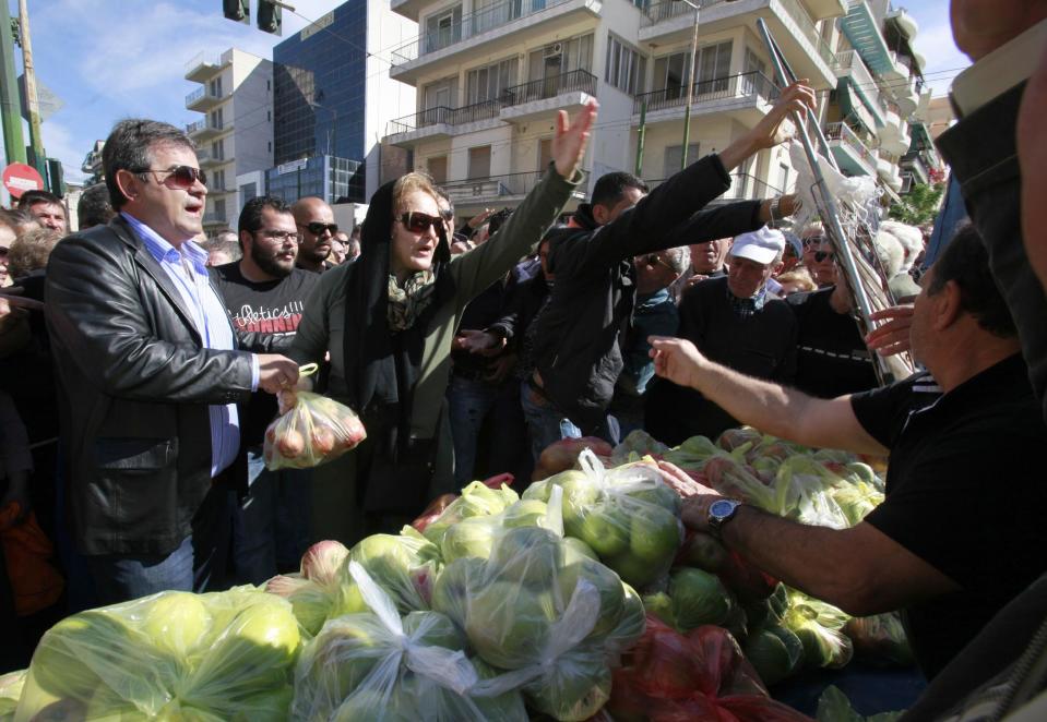 Greek farmers' market vendors distribute free products as part of a protest in Athens, Wednesday, April 30, 2014, after their trading association launched an indefinite strike Monday. The market vendors are the latest professional group in Greece to protest a sweeping liberalization drive demanded by rescue creditors. (AP Photo/Dimitri Messinis)