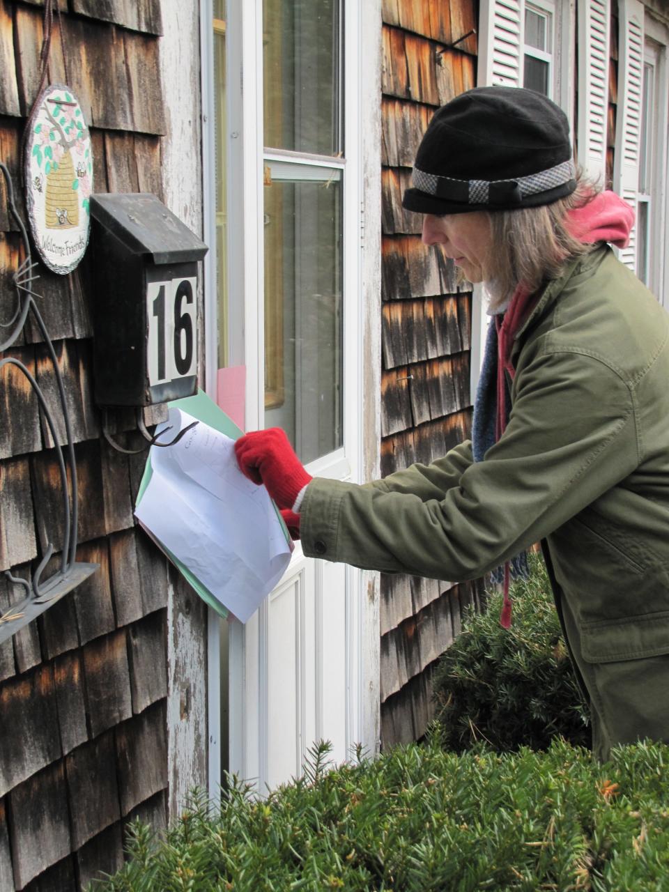 Activist Diane Turco leaves a flyer on a Hyannis home on April 30. Occupy Hyannis activists distributed the flyers that call for protests in neighborhoods where foreclosures have been concentrated.