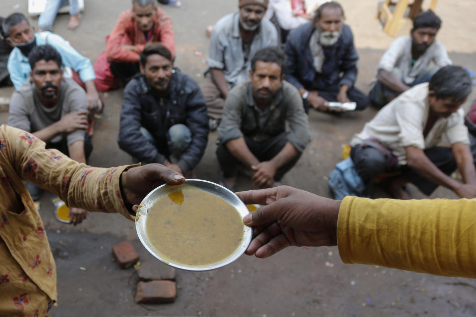FILE - People wait for free food outside an eatery in Ahmedabad, India, on Jan. 20, 2021. Growing numbers of people in Asia lack enough food to eat as food insecurity rises with higher prices and worsening poverty, according to a report by the Food and Agricultural Organization and other UN agencies released Tuesday, Jan. 24, 2023. (AP Photo/Ajit Solanki, File)