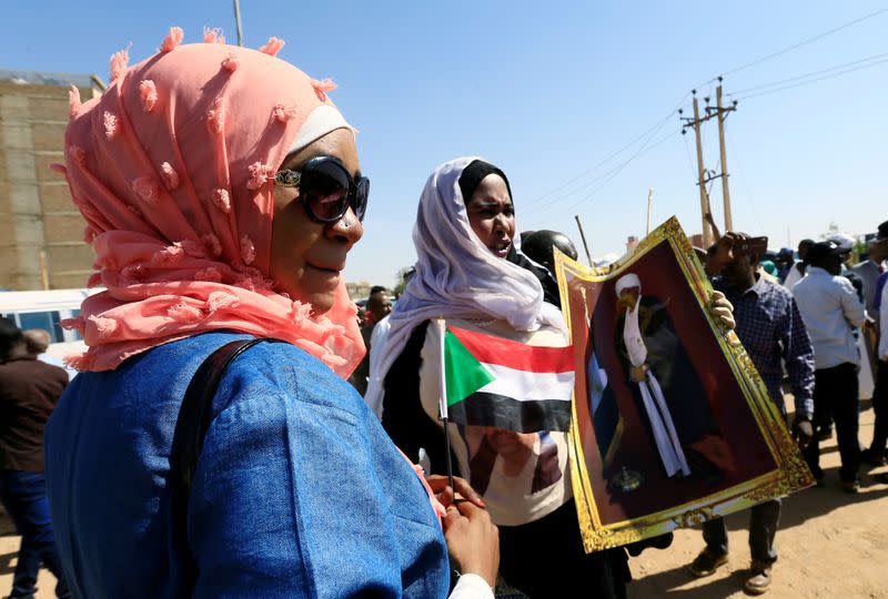 Supporters of Sudanese former president Omar Hassan al-Bashir carry his picture during a protest outside the court house that convicted him on corruption charges in Khartoum