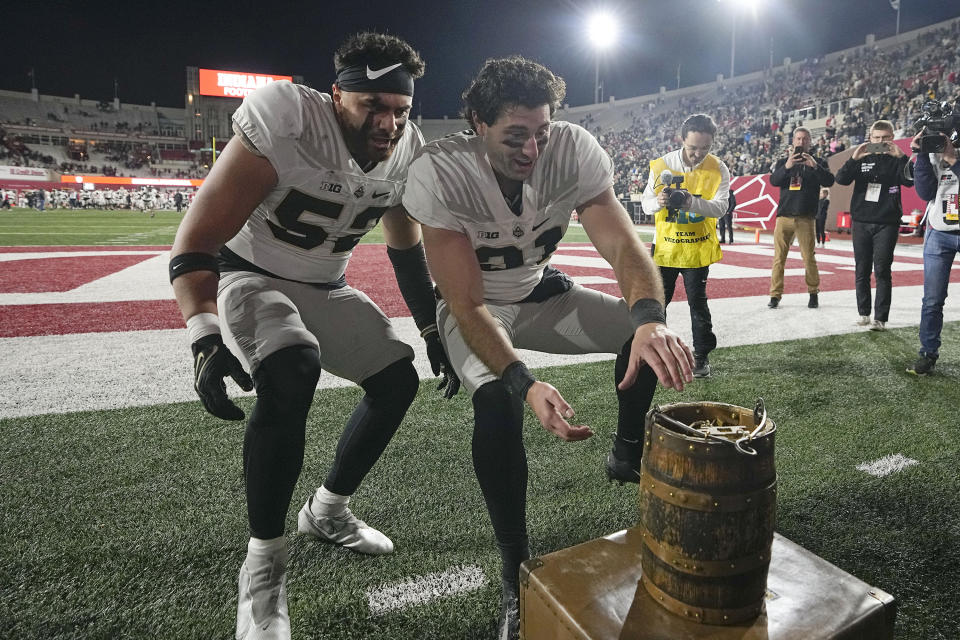 Purdue's Zac Tuinei (52) and Nick Zecchino (31) grab the Old Oaken Bucket after defeating Indiana in an NCAA college football game, Saturday, Nov. 26, 2022, in Bloomington, Ind. (AP Photo/Darron Cummings)