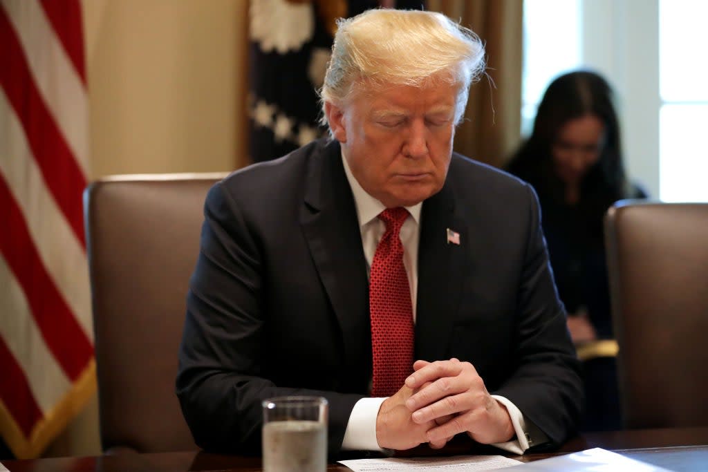 President Donald Trump closes his eyes during a prayer before a meeting of his cabinet in the Cabinet Room at the White House: Getty