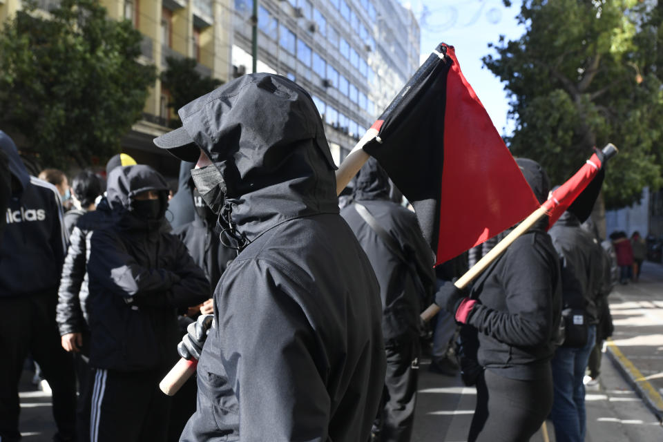 A hooded protester holds a flag during a rally in Athens, Greece, on Monday Dec. 6, 2021. Hundreds of protesters marched the streets of the Greek capital, on the 13th anniversary of the 15-year old Alexis Grigoropoulos' fatal shooting by the police. (AP Photo/Michael Varaklas)