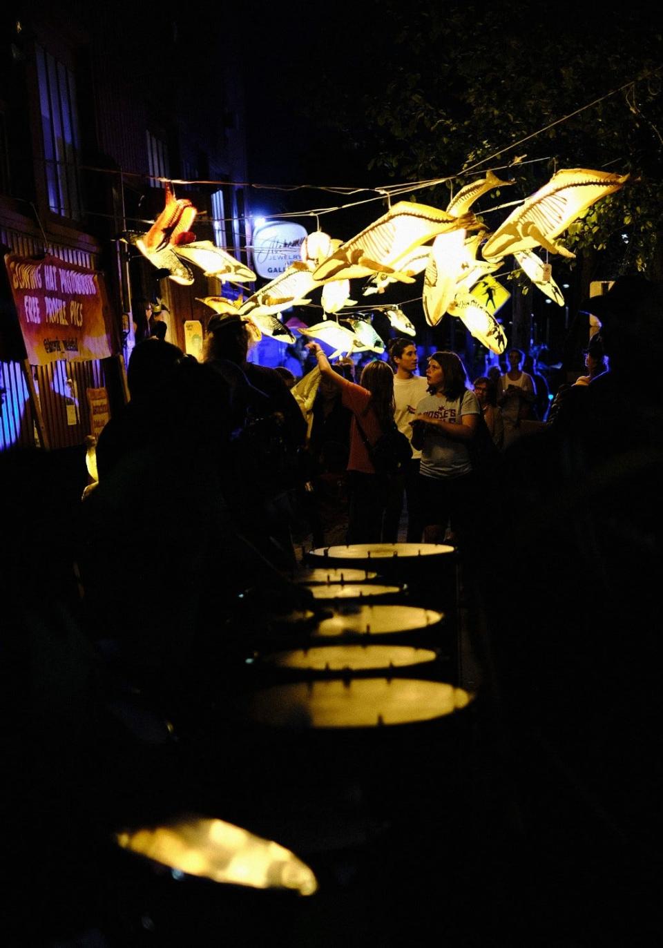 Lights from paper whale lanterns reflect off the skins of drums play by the 
Sambatucada! group along Pine Street at the South End Art Hop on Friday, Sept. 6, 2019.