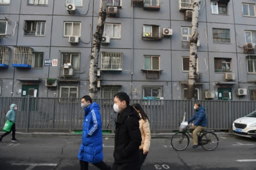 Beijing residents, wearing face masks, walk past a residential building -- the new-coronavirus death toll exceeds that of the 774 killed worldwide by SARS