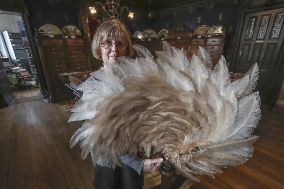 Anne Hoguet, 74, fan-maker and director of the hand fan-making museum poses with a feather fan at the museum in Paris, Wednesday, Jan. 20, 2021. Just like the leaves of its gilded fans, France's storied hand fan-making museum could fold up and vanish. The splendid Musee de l'Eventail in Paris, a classed historical monument, is the culture world's latest coronavirus victim. (AP Photo/Michel Euler)