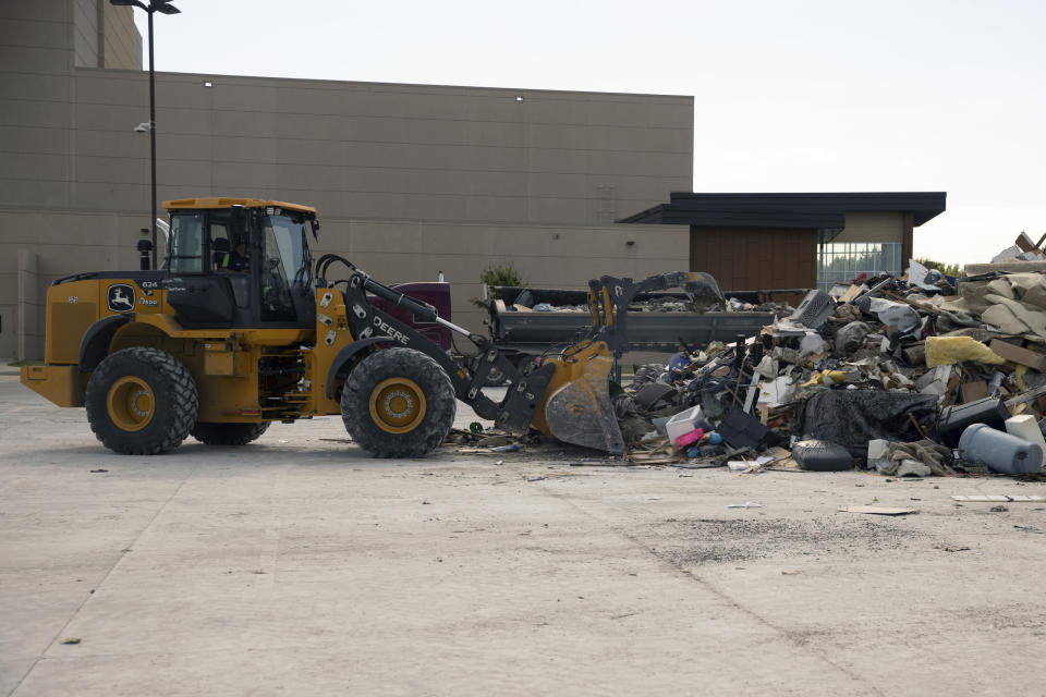 A Skid Loader scoops up debris after residents were forced to dump trash at the high school after being unable to access the city dump while trying to clean up after flooding over the weekend, Wednesday, June 26, 2024, in Canton, SD . (AP Photo/Josh Jurgens)