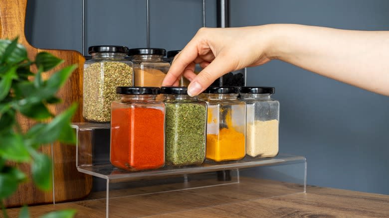 Hand picking spices from spice rack