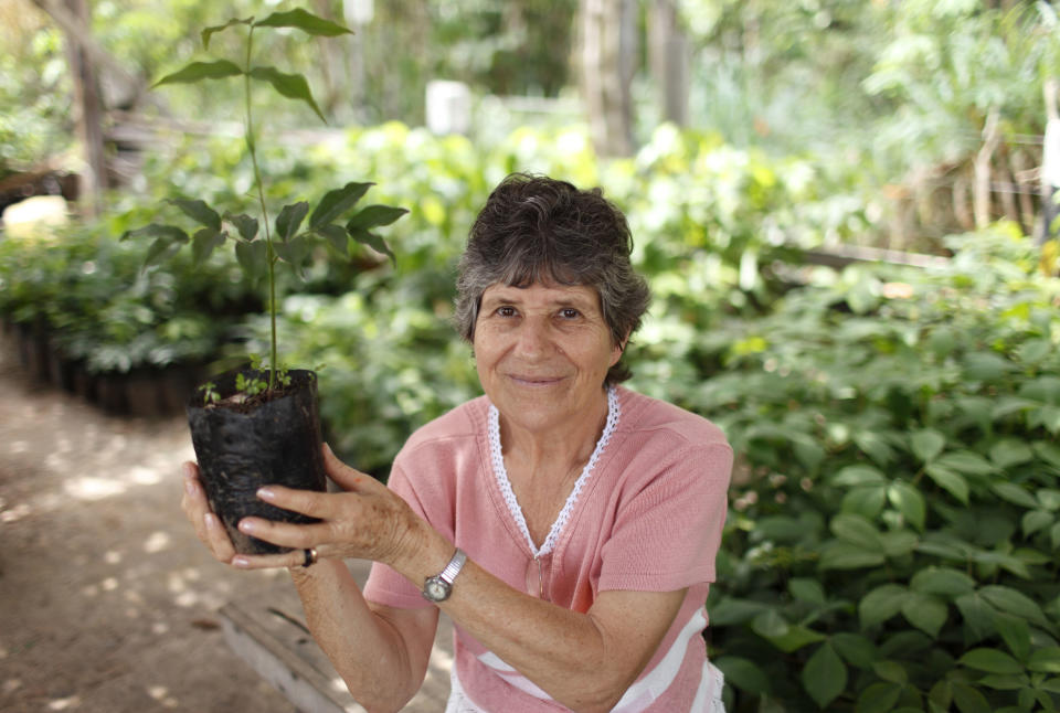 FILE - In this Sept. 21, 2009, file photo, land activist Leonora Brunetto, a Roman Catholic nun, holds up a young tree near Alta Floresta, Brazil. Brunetto was violently killed in 2010 after she spent decades defending poor, landless workers, and collecting countless threats from ranchers she blocked from stealing Amazon land. Global Witness said Tuesday, July 24, 2018 that at least 207 people who were protecting land and resources from business interests were slain last year. (AP Photo/Andre Penner, File)