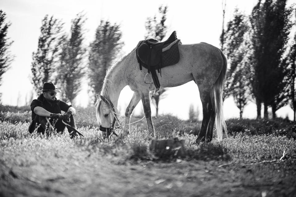 Young man in a cowboy hat riding his horse in the past. black and white