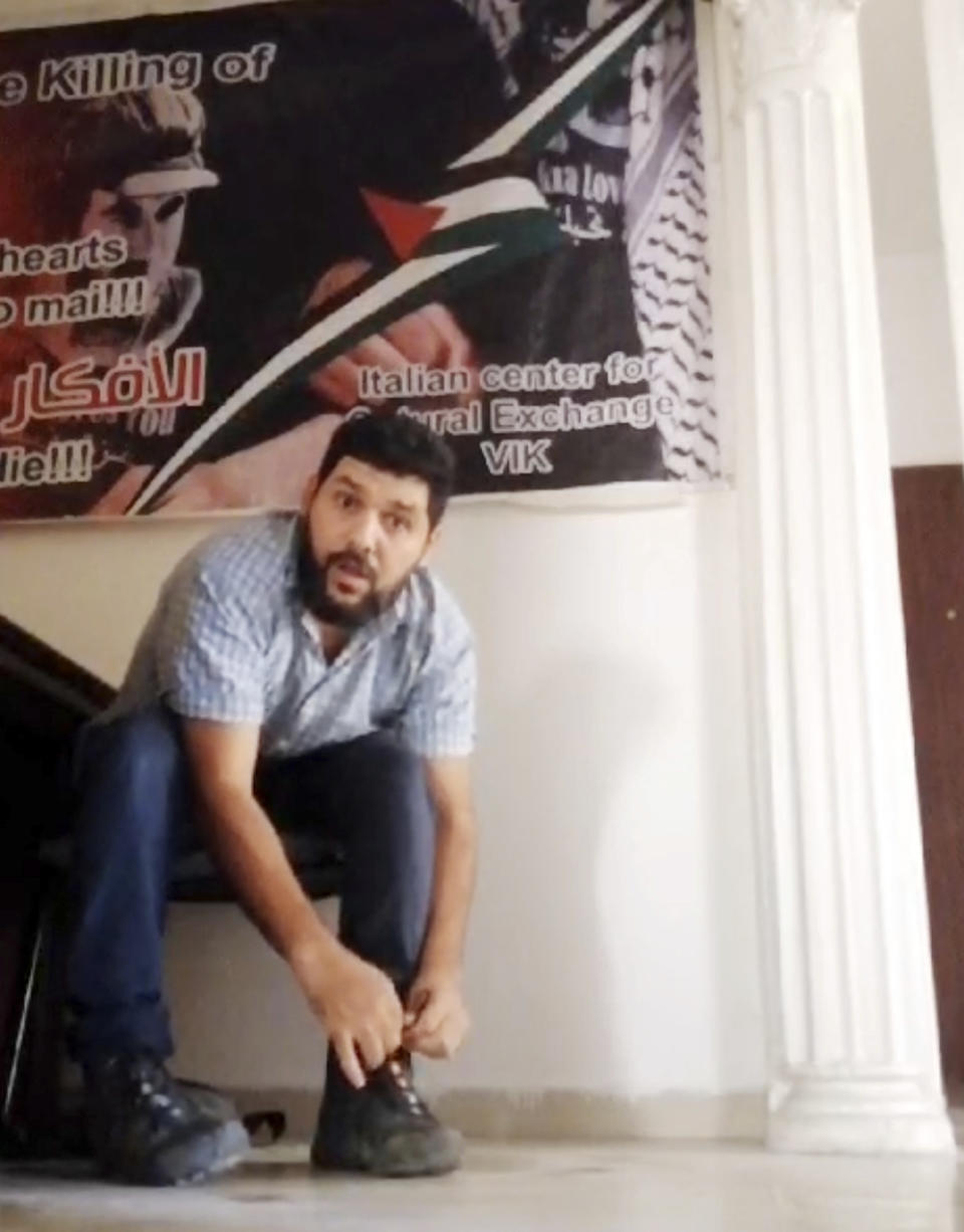 Image taken from Oct. 11, 2023 video provided by Asaad Alaadin, Asaad Alaadin ties his boots as he prepares to flee an office in central Gaza City after bombs began to fall all around him. Alaadin, a writer, set out with his family on Oct. 13, 2023, the day Israel’s military ordered 1 million Palestinians in northern Gaza to evacuate. (Asaad Alaadin via AP)