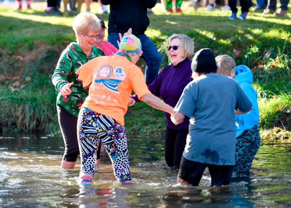 Friends from a senior strength class hold hands Saturday as they wade into Penns Creek for the YMCA of Centre County Polar Bear Plunge.