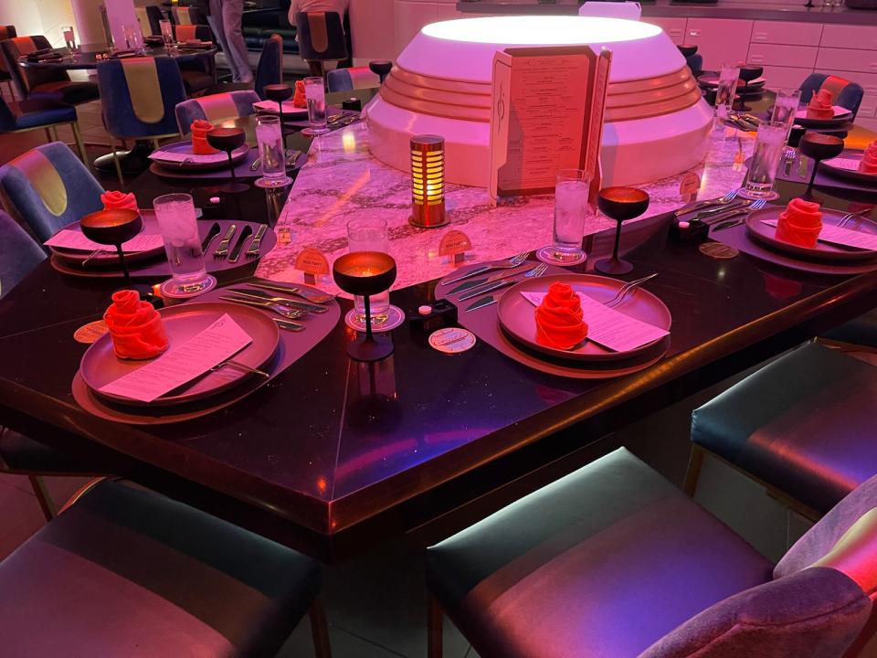 a photo of the captains table in the Starcruiser, which has folder napkins and glases around a funky-shaped dark table