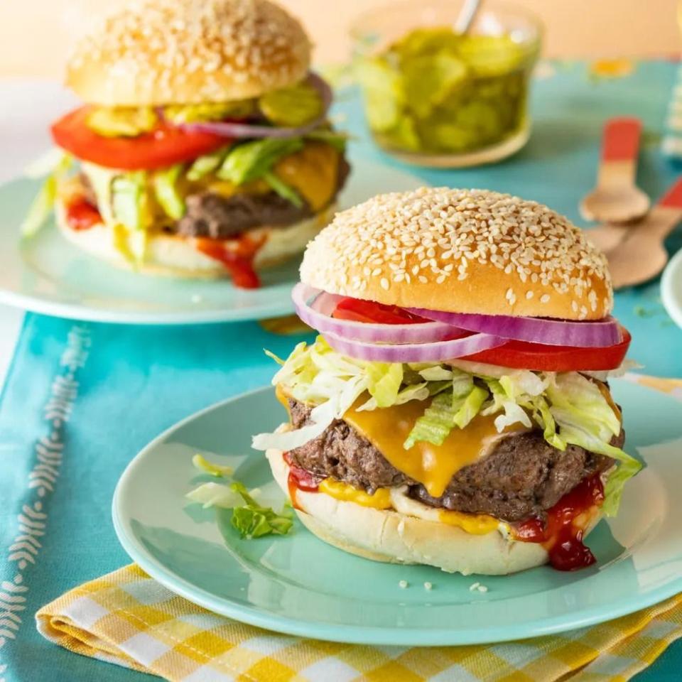 classic cheeseburger with onions tomato and lettuce on teal plate