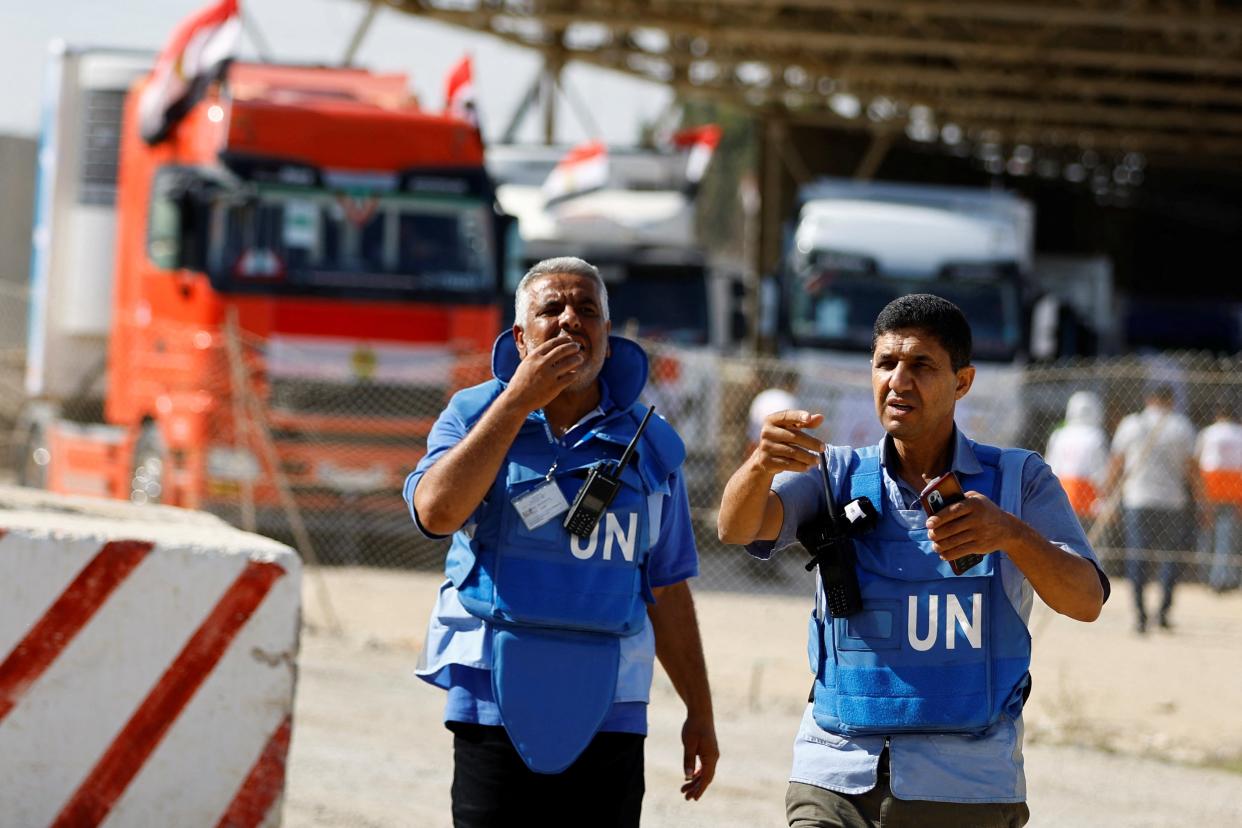 UN workers gesture as trucks carrying aid arrive at the Palestinian side of the border with Egypt (REUTERS)