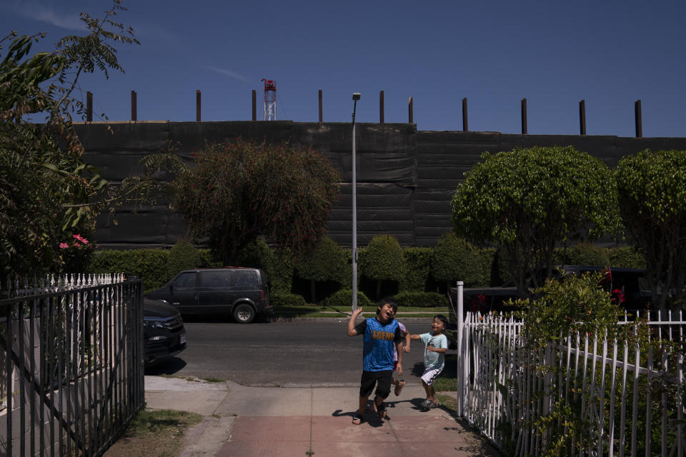 FILE - Children chase one another outside their home across the street from the Jefferson oil drill site enclosed by tall fences in Los Angeles, June 2, 2021. Stop the Energy Shutdown, a campaign organized by oil and gas industry groups, said Tuesday, Dec. 13, 2022, it has collected enough signatures for a referendum to overturn SB 1137, the law that banned new oil and gas wells within 3,200 feet of highly populated places. (AP Photo/Jae C. Hong, File)