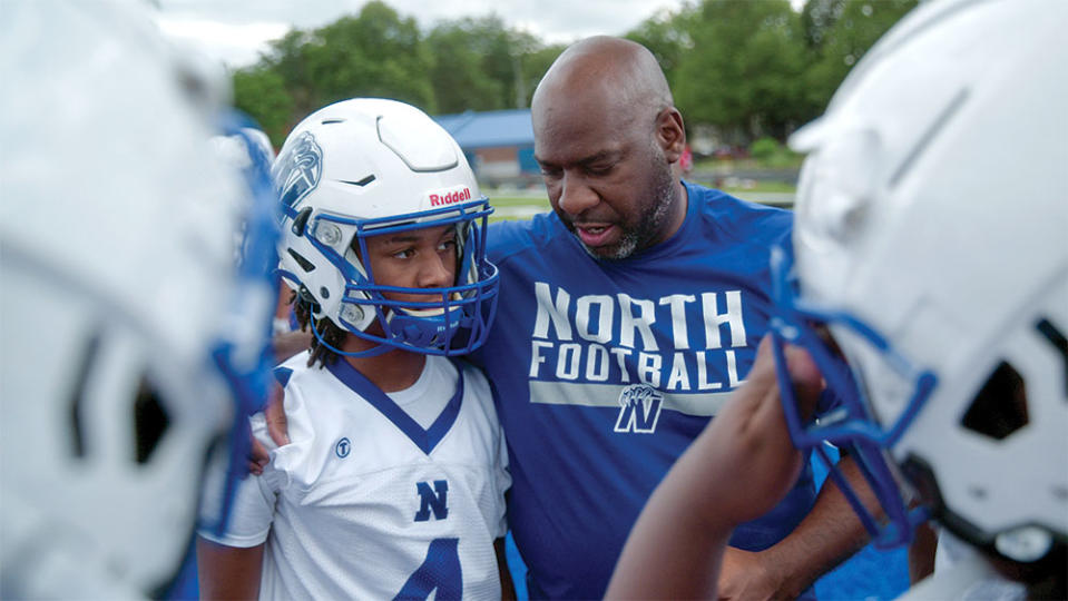 Minneapolis police officer Ricky Plunkett and a player from the North Community High School football team that Plunkett coaches