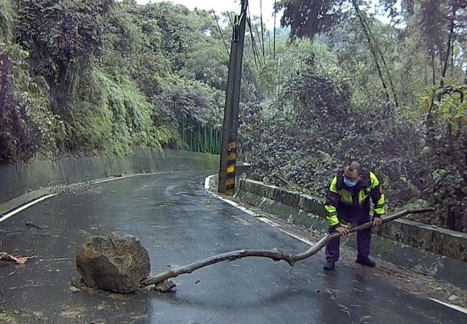 潭子區新田登山步道落石影響交通，員警靈機一動以木頭及石塊產生支點將該落石撐起，讓交通恢復順暢。（記者陳金龍翻攝）