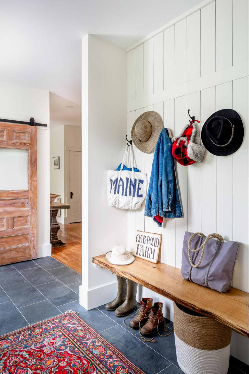 Floor to ceiling tongue and groove, wood bench, dark tile floor, red vintage rug, hooks for hats and bags