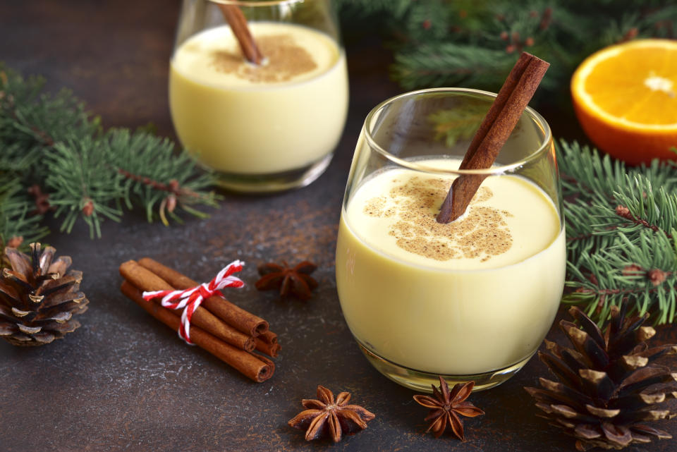 Winter spicy hot drink eggnog in a glasses on a dark slate, stone or concrete background.