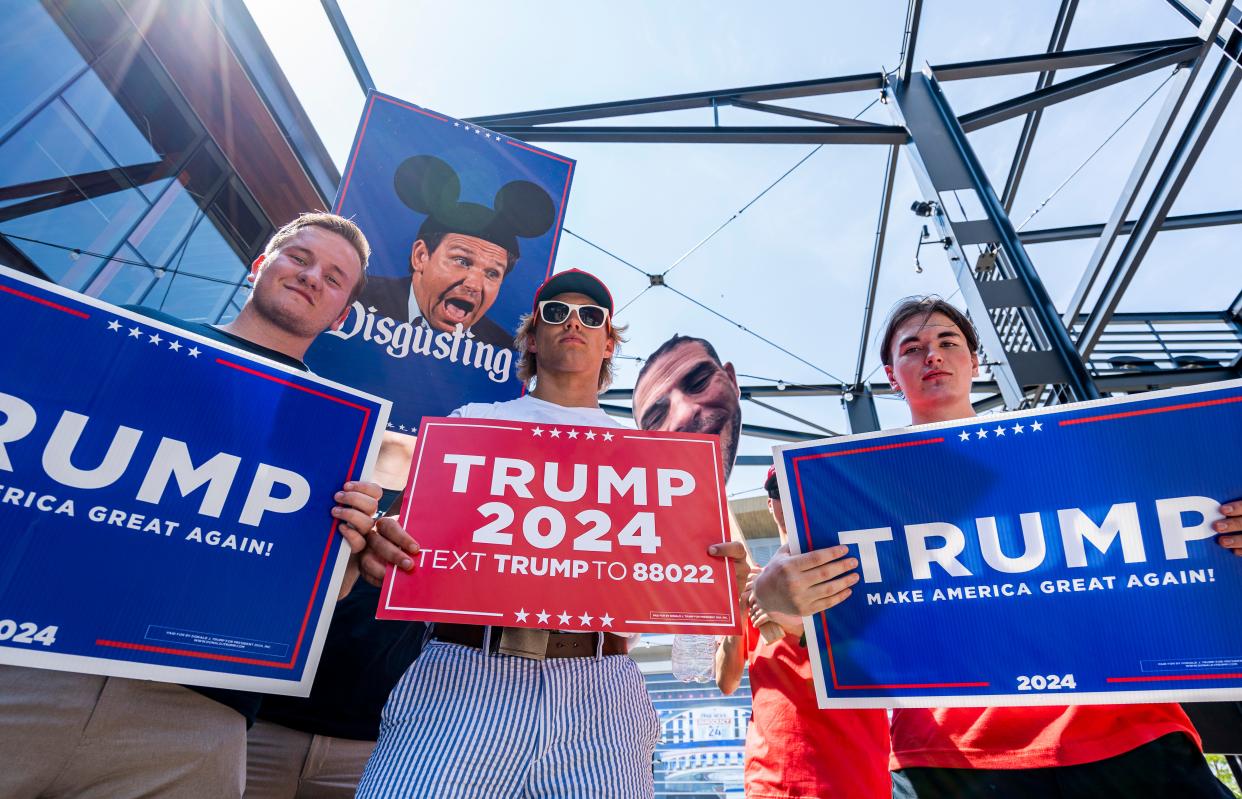 Volunteers with the Trump campaign carry signs in front of the Fiserv Forum as the RNC is kicking off their 2024 primary election with a debate in Milwaukee on Wednesday August 23, 2023 in Milwaukee, Wis.