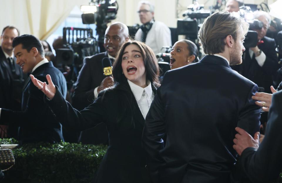 Billie Eilish yells out as brother Finneas stands next to her.