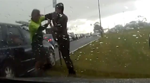 The man and woman scrap as stunned motorists look on. Source: 7 News