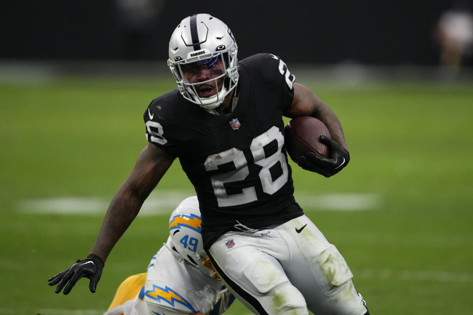 Las Vegas Raiders running back Josh Jacobs (28) carries against Los Angeles Chargers linebacker Drue Tranquill (49) during the first half of an NFL football game, Sunday, Dec. 4, 2022, in Las Vegas. (AP Photo/Matt York)