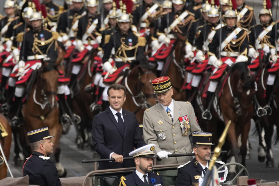 French President Emmanuel Macron attends with French Chief of the Defense Staff, General Thierry Burkhard, at the Bastille Day parade on the Champs-Elysees avenue in Paris, Friday, July 14, 2023. (AP Photo/Christophe Ena)