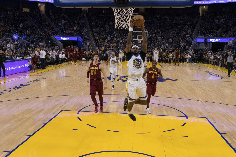 Golden State Warriors guard Gary Payton II (0) dunks in front of Cleveland Cavaliers forward Cedi Osman (16) and guard Rajon Rondo (1) during the first half of an NBA basketball game in San Francisco, Sunday, Jan. 9, 2022. (AP Photo/John Hefti)