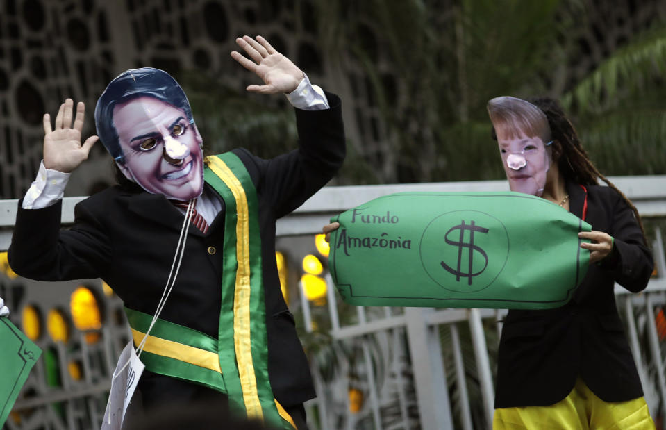 Demonstrators wear masks of Brazil's President Jair Bolsonaro, left, and Germany's Chancellor Angela Merkel during a protest in defense of the Amazon in Rio de Janeiro, Brazil, Thursday, Sept. 5, 2019. Germany has suspended a line of funding for Amazon projects. (AP Photo/Silvia Izquierdo)