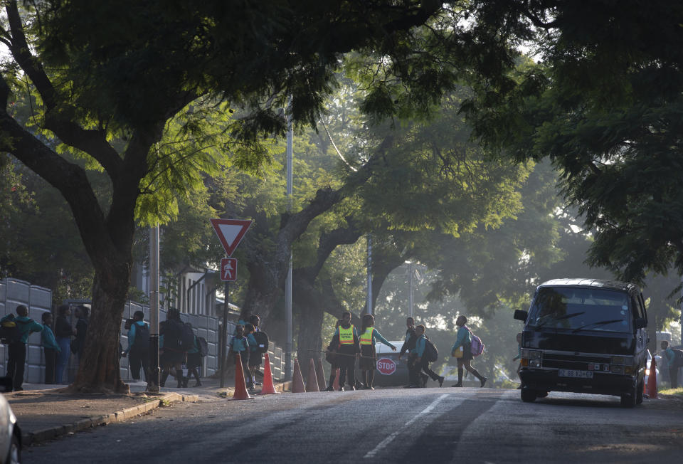 Children make their way to school in Johannesburg Monday, March 16, 2020 a day after President Cyril Ramaphosa declared a national state of disaster. Ramaphosa said all schools will be closed for 30 days from Wednesday and he banned all public gatherings of more than 100 people. South Africa will close 35 of its 53 land borders and will intensify screening at its international airports. For most people, the new COVID-19 coronavirus causes only mild or moderate symptoms. For some it can cause more severe illness. (AP Photo/Denis Farrell)