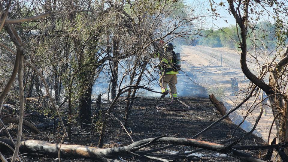 Amarillo firefighters hose down a burnt area outside a scrap yard on Lamar Saturday.