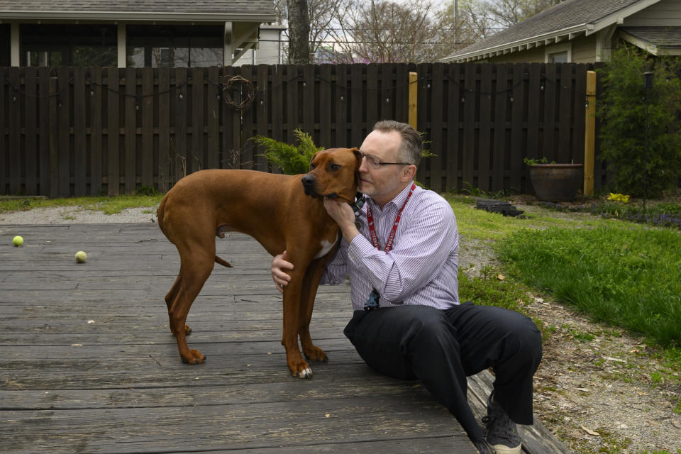 Chaplain Matthew Sullivan spends time with his dog Hank after coming home from work at The Covenant School Friday, March 22, 2024, in Nashville, Tenn. Nearly a year after a shooting at the christian elementary school that left six dead, many of the school's families have adopted dogs in dealing with their shared suffering. (AP Photo/John Amis)