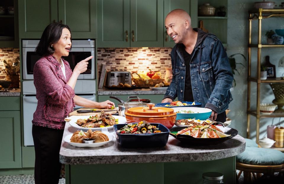 a man and a woman stand by a table full of food