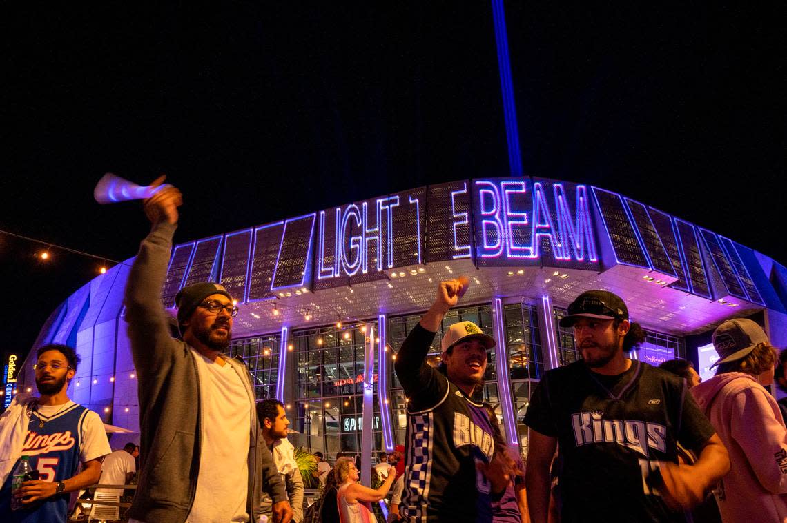 Sacramento Kings fans Felipe Rodriguez, left, Giovanni Jimenez, center and Daniel Montoya, celebrate by ringing cowbells and waving light beams outside after they lit the beam on top of Golden 1 Center to celebrate their win over the Golden State Warriors on Saturday, April 15, 2023, in round one of the playoffs.