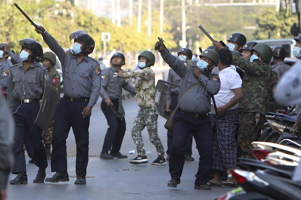 FILE - In this Feb. 15, 2021, file photo, a policeman aims a slingshot towards an unknown target during a crackdown on anti-coup protesters holding a rally in front of the Myanmar Economic Bank in Mandalay, Myanmar. The escalation of violence in Myanmar as authorities crack down on protests against the Feb. 1 coup is adding to pressure for more sanctions against the junta, as countries struggle over how to best confront military leaders inured to global condemnation.(AP Photo/File)