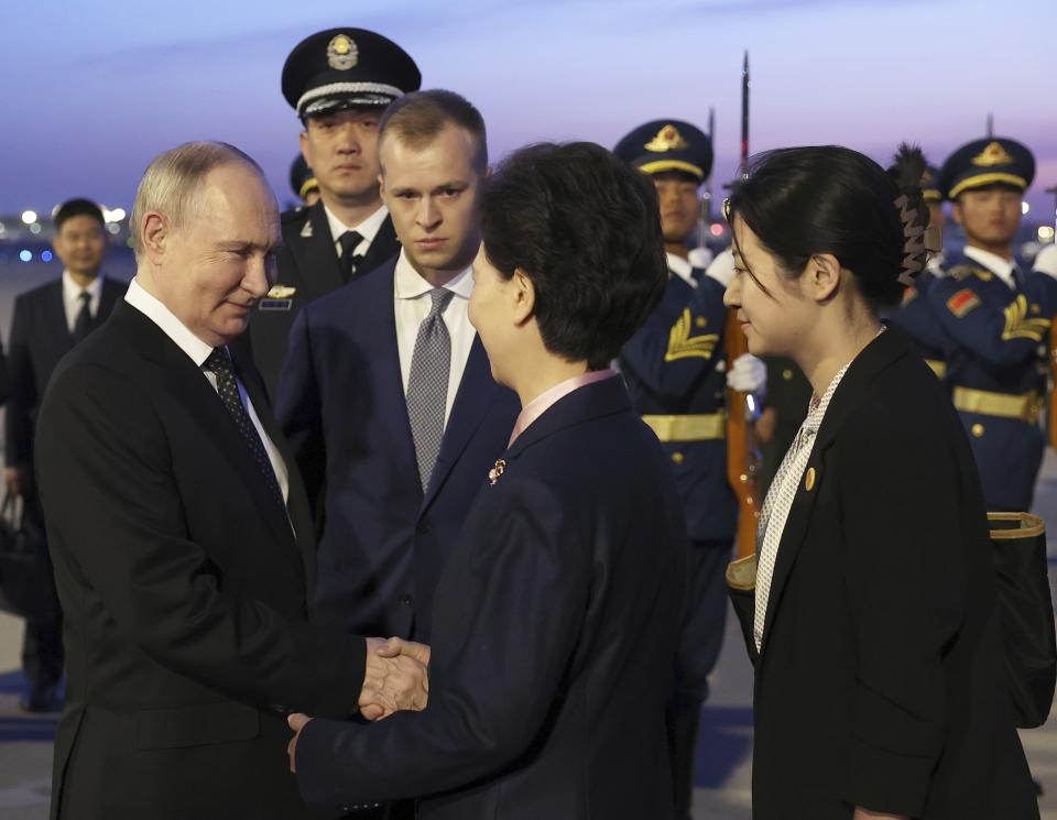 El presidente ruso Vladímir Putin (izquierda) estrecha la mano de la consejera de Estado de China, Shen Yiqin (segunda por la derecha), a su llegada el 16 de mayo de 2024 al aeropuerto internacional de Beijing, China. (Alexander Ryumin, Sputnik, foto compartida del Kremlin vía AP)