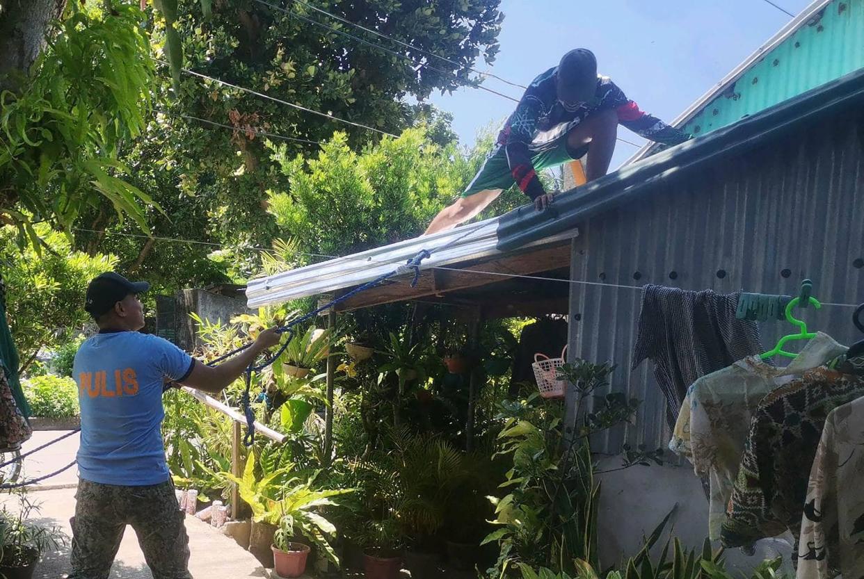 Police help residents reinforce the roof of their homes in Ivana town, Batanes province, on the very tip of the Philippines, ahead of super Typhoon Mawar grazing the province (Ivana Police station/AFP via Getty)