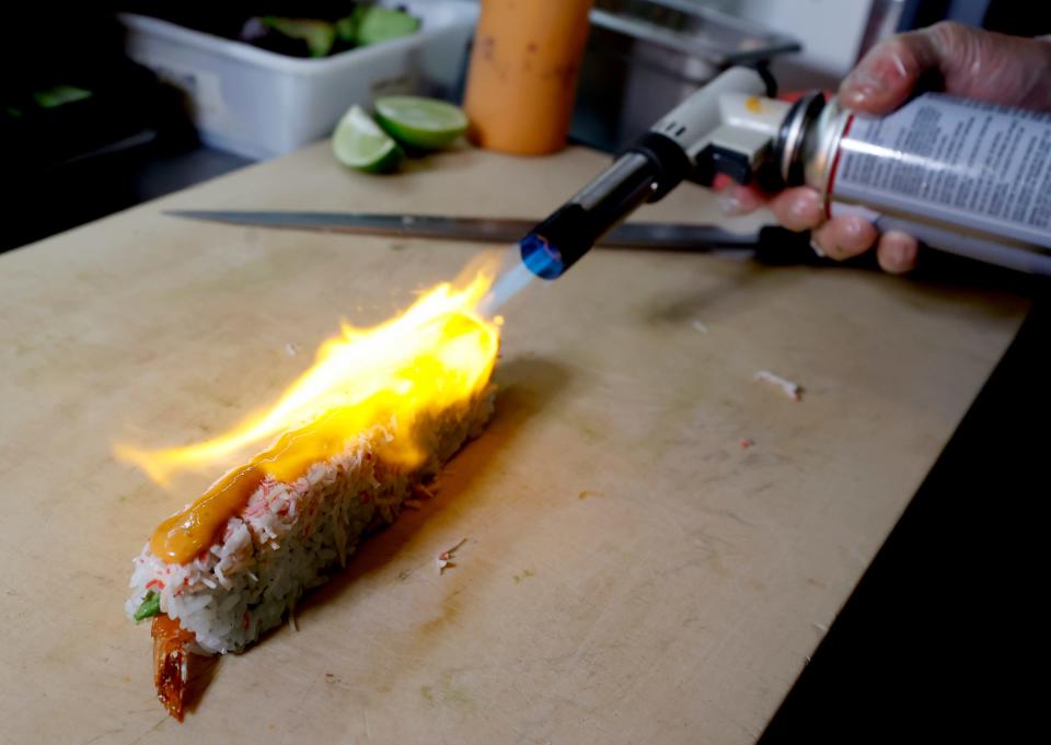 Sushi chef Youkichi Koshizawa at at Zao Jun torches spicy mayo on a firecracker sushi roll at New Asian restaurant in Bloomfield Township, Mich., on Jan. 24.