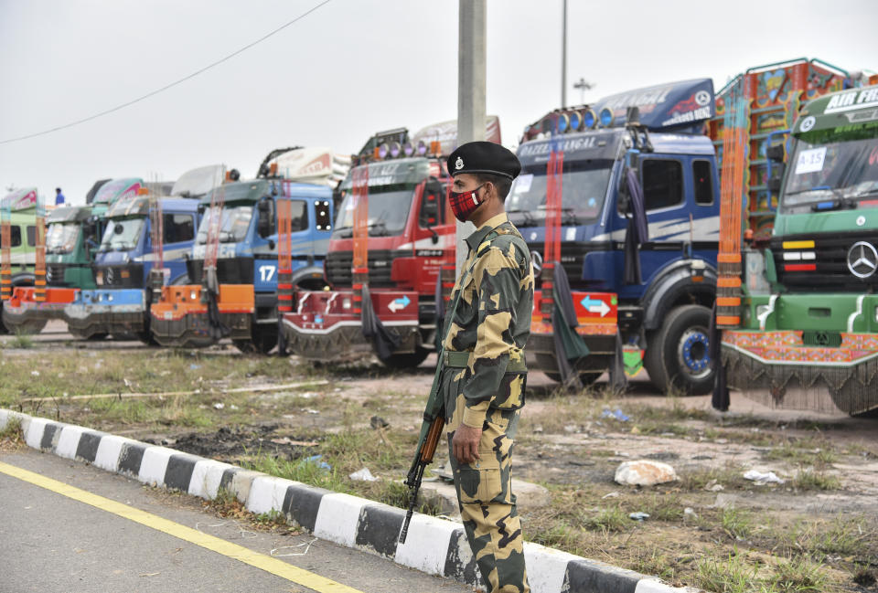 An Indian Border Security Force soldier guards as trucks carrying wheat from India wait to pass through the Attari-Wagah border between India and Pakistan, near Amritsar, India, Tuesday, Feb.22, 2022. Last week, Pakistan officials said the country would allow nuclear rival India to deliver wheat to Afghanistan, where millions are struggling through acute food shortages. The arrangement comes more than three months after India announced it would deliver 50,000 metric tons of wheat and life-saving medicine to Afghanistan. (AP Photo/Prabhjot Gill)