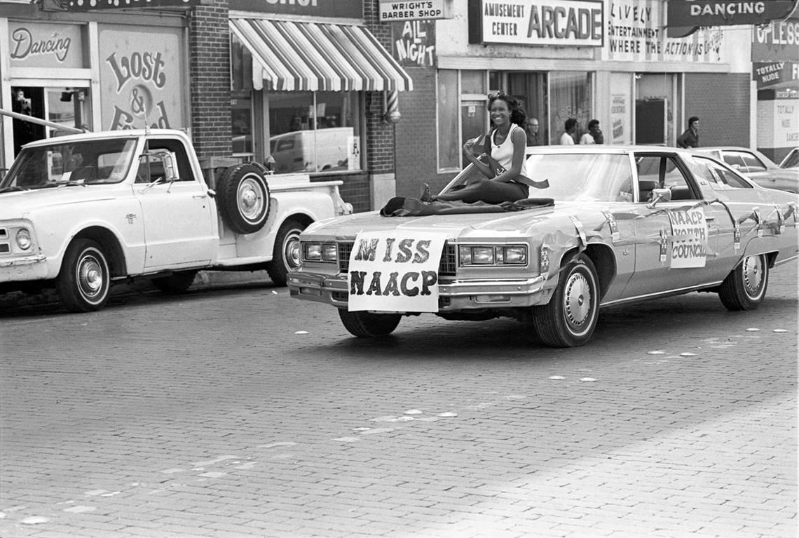 Miss NAACP is seen riding on the hood of a car driving along Main Street in downtown Fort Worth for the Juneteenth parade in 1978.