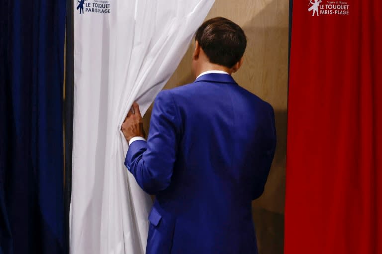 Le président Emmanuel Macron entre dans l'isoloir pour voter au premier tour des élections législatives dans un bureau de vote du Touquet, dans le Pas-de-Calais, le 30 juin 2024 (Yara Nardi)