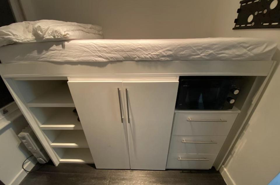The space inside the apartment has no kitchen, just a microwave below the bed.