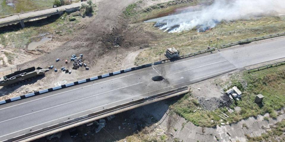 An aerial view of a damaged bridge in Crimea, with a large hole in it plume of smoke nearby, as Ukraine announces a Storm Shadow strike on August 6, 2023