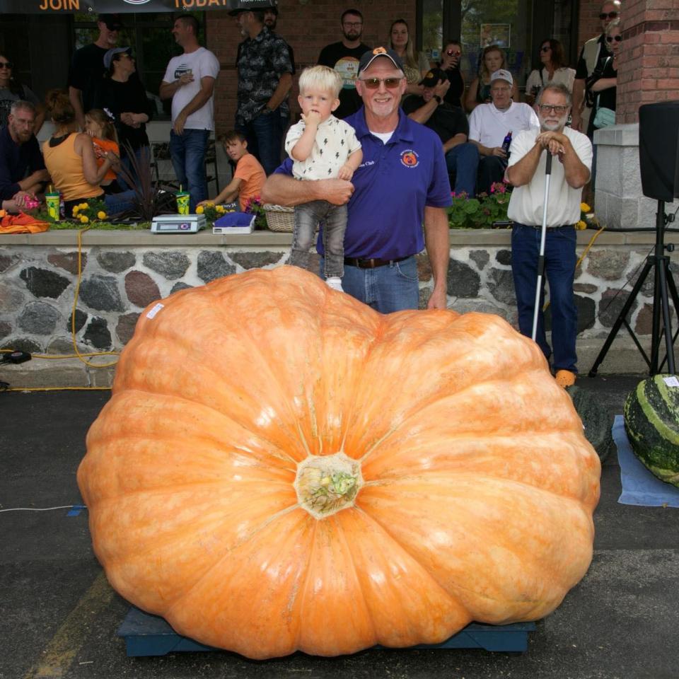 Pumpkin grower Tom Montsma poses with "the baby of the patch" and his 2,360-lb. giant pumpkin.