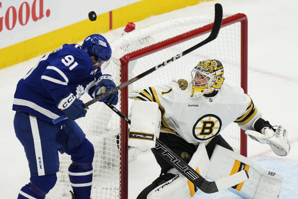 Toronto Maple Leafs' John Tavares (91) is hit by the puck as Boston Bruins goaltender Jeremy Swayman (1) watches during the first period on Game 3 of an NHL hockey Stanley Cup first-round playoff series in Toronto on Wednesday, April 24, 2024. (Frank Gunn/The Canadian Press via AP)
